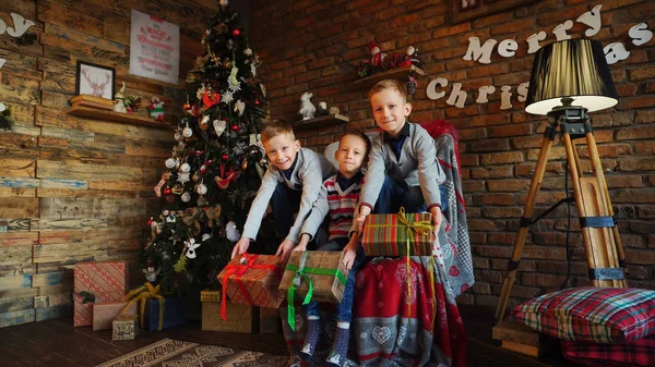 Três irmãozinhos se alegram com presentes de Natal — Fotografia de Stock