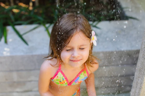 小さな少女は目を閉じてに落ちる水の滴を太陽の光の肖像画 — ストック写真