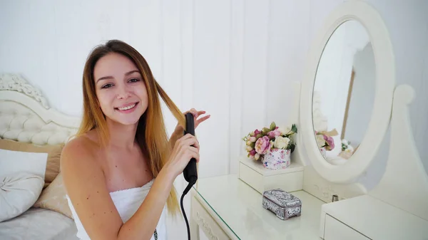 Mujer joven agraciada apila el cabello mediante el uso de pelo estilista, sentado en la silla — Foto de Stock