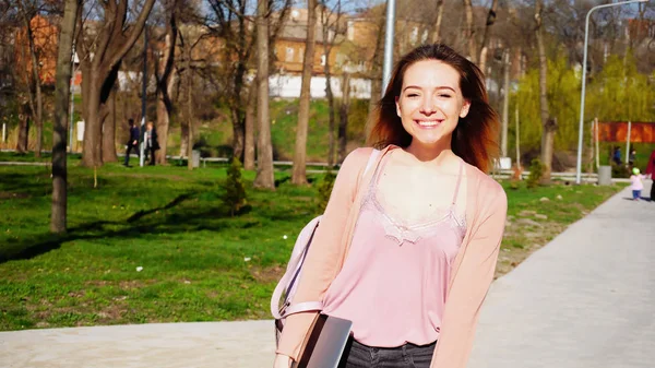 Felice studente a piedi dopo le lezioni vicino al parco con smartphone e — Foto Stock