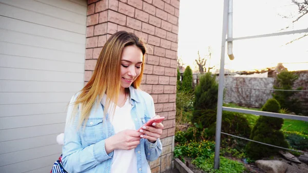 Chica joven con cerca de escribir las manos por teléfono inteligente de pie nea — Foto de Stock