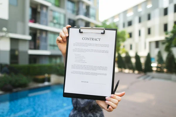 Enfoque en el contrato, que está en manos de la joven contra el trasfondo — Foto de Stock