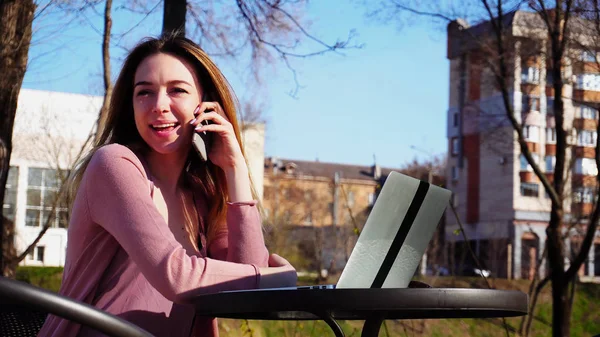 Mujer joven hablando por teléfono inteligente y la navegación por ordenador portátil en fres — Foto de Stock