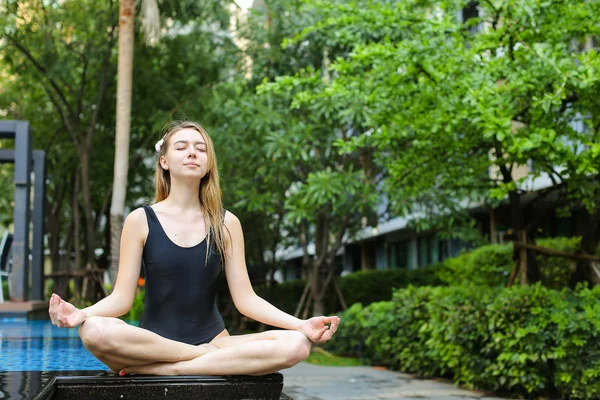 Mujer cerrar los ojos sentado en posición de loto, haciendo yoga por el po — Foto de Stock