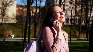 Parkta yürümek ve konuşmak smartphone tarafından neşeli öğrenci.