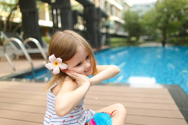 Lindo niño niña humana pequeña sentada cerca de la piscina usando — Foto de Stock