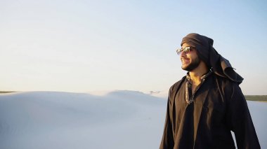 Kendine güvenen erkek yakışıklı Arap Kandur içinde beyaz ortasında yürüyor 