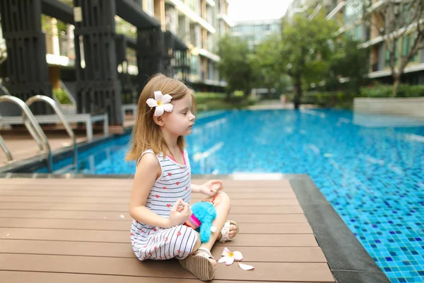 Niño haciendo ejercicios de yoga sentado cerca de la piscina w — Foto de Stock