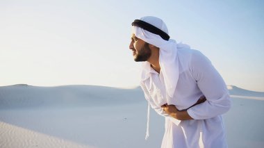 Young male emirate suffers from severe pains in abdomen, standin clipart