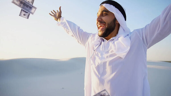 Successful Arab sheikh considers banknotes and happy, standing i