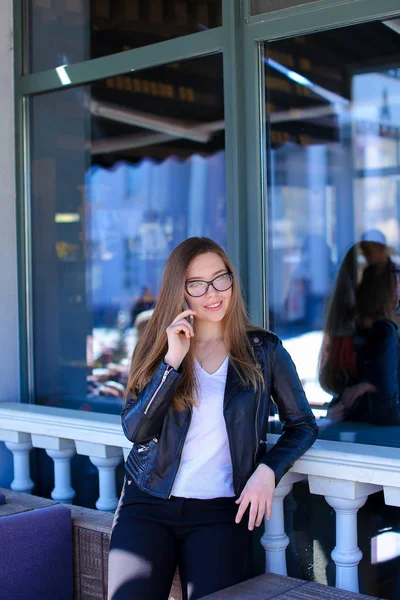 Mulher alegre em óculos falando no smartphone no café de rua . — Fotografia de Stock