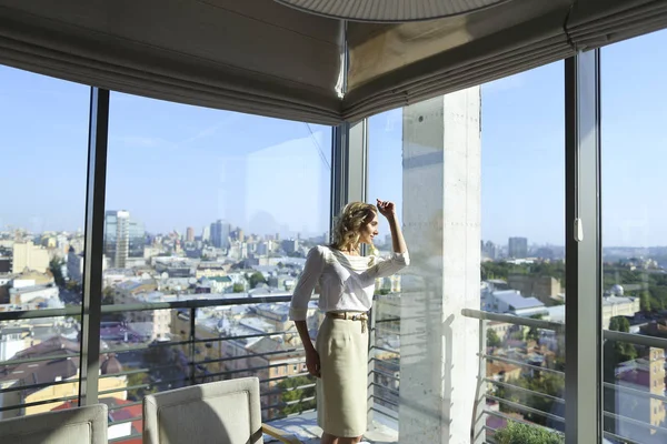Female person standing at restaurant near window with cityscape background.
