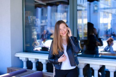 Genç kız Smartphone ile pencere yakınındaki sokak kafede konuşuyor.