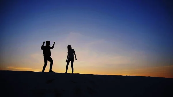 Веселый парень и девушка веселятся и танцуют на вершине песчаной дюны — стоковое фото