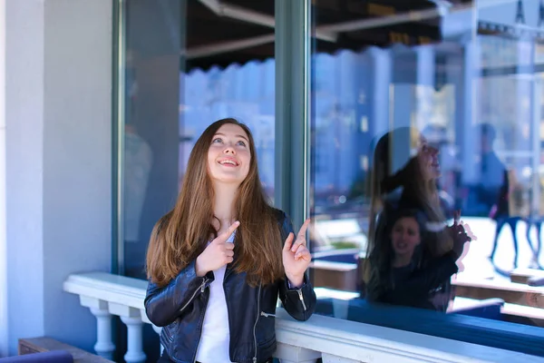 Mädchen steht mit Zeigefingern am Fenster eines Straßencafés. — Stockfoto