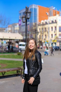 Şehirde yürüyüş ve deri ceket giymiş güzel kadın kişi.
