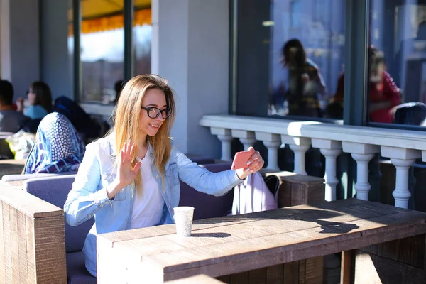 Chica haciendo selfie por teléfono inteligente y sentado en la cafetería con taza de té . — Foto de Stock
