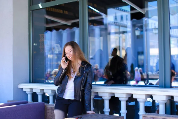 Νεαρό άτομο μιλάμε από το smartphone στην καφετέρια του δρόμου. — Φωτογραφία Αρχείου