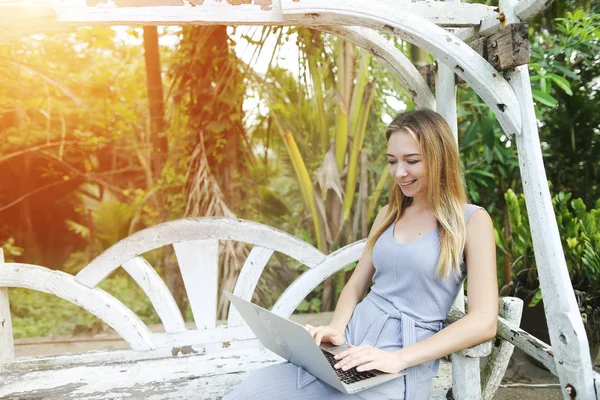 Mujer rubia utiliza el ordenador portátil para el trabajo remoto en el día soleado, fondo de palmas verdes sol en Tailandia, viajes Phuket — Foto de Stock