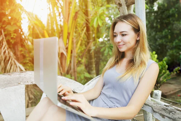 Rubia mujer feliz utiliza la computadora PC para el trabajo en el día soleado, fondo de sol palmas verdes en Tailandia, viajes Phuket — Foto de Stock