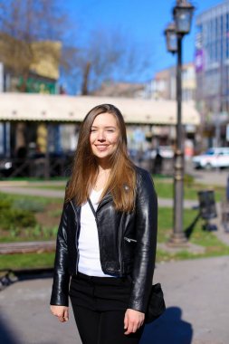 Genç kadın walkign şehir ve giyen deri ceket.