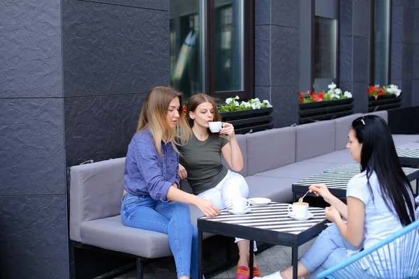 Jóvenes amigas tomando café y sentadas en la cafetería . — Foto de Stock