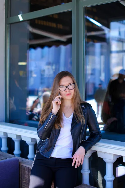 Симпатична жінка в окулярах розмовляє по смартфонах у вуличному кафе . — стокове фото