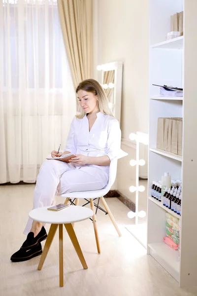Jonge psyhologist schrijven in laptop tegen een kabinet en dragen witte pak. — Stockfoto