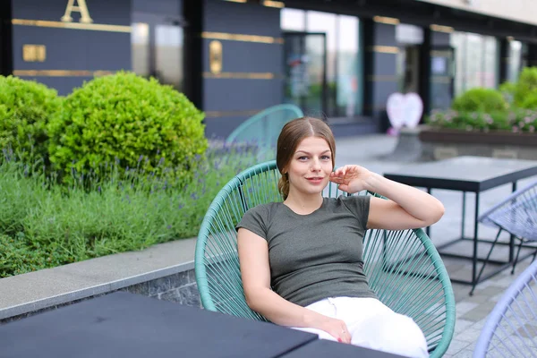 Pessoa feminina descansando no café de rua e sentado perto de planta verde . — Fotografia de Stock