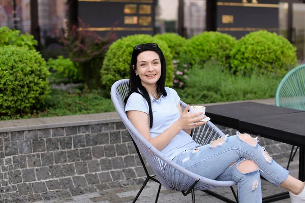 Señora sentada en la silla en el café cerca de las plantas verdes y beber café . — Foto de Stock