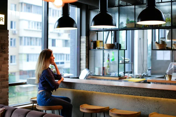 Jente som sitter i bar på kafe og går med jeans . – stockfoto