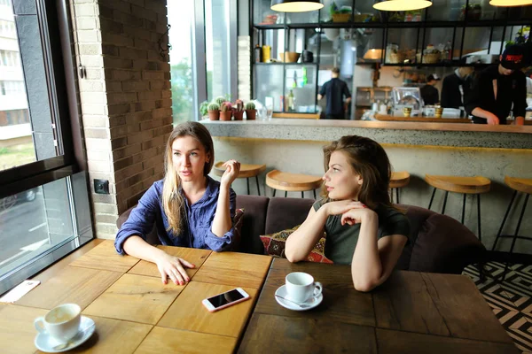 Positive cute women sitting at cafe with cups of coffee and smiling. — Stock Photo, Image