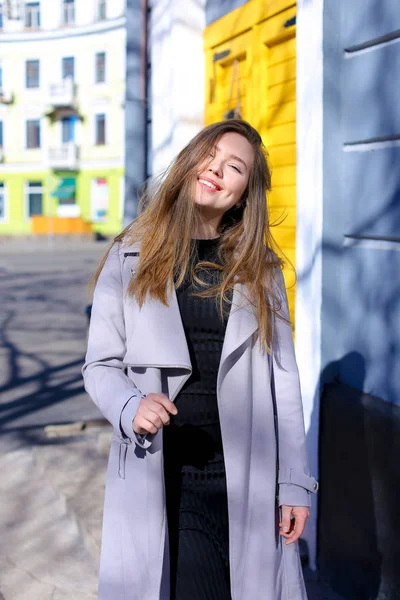 Chica paseando al aire libre cerca de la cafetería y usando abrigo gris con vestido negro . —  Fotos de Stock