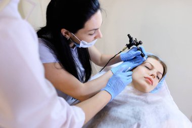 Kadın güzellik uzmanı kadın için dövme yordam tarafından makinesi.