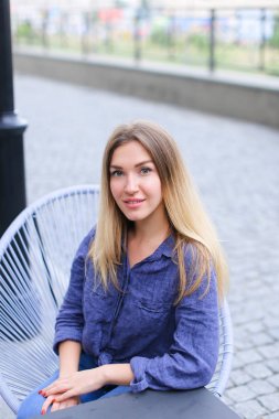 Kafede oturan ve mavi gömlek giymiş güzel kadın.