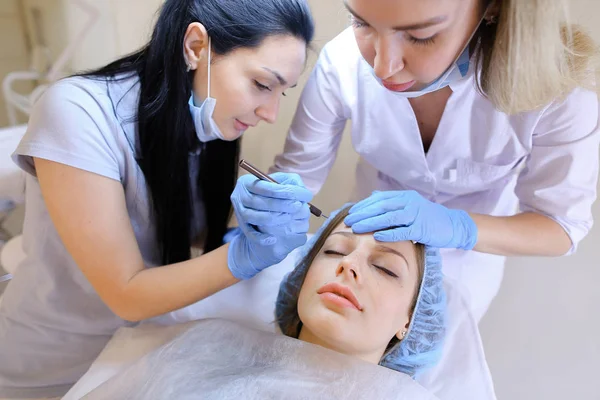 Young female person visiting professional dermatologist and cosmetologist for permanent makeup.