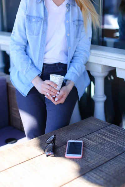 Persona femenina bebiendo té cerca de vasos y teléfonos inteligentes . — Foto de Stock