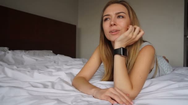 Mladá ženská osoba chatování o chytré hodinky a odpočívá v posteli — Stock video