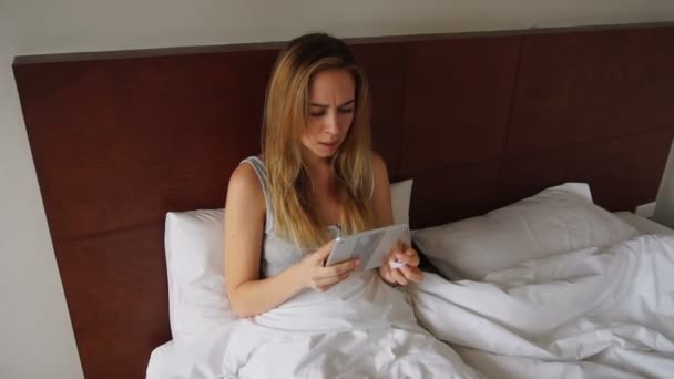 Kranke Frau liegt mit laufender Nase im Bett und sucht per Tablet nach Informationen. — Stockvideo