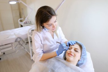 Gülümseyen kadın makyaj güzellik uzmanı tarafından kaş dövme kalemi tarafından elde.