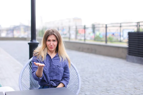 Jovem mulher descontente sentado no café de rua e fazendo rostos . — Fotografia de Stock