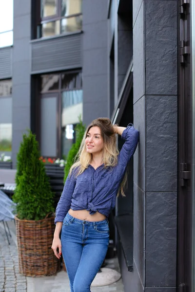 Jolie fille debout près du bâtiment et de la plante verte . — Photo