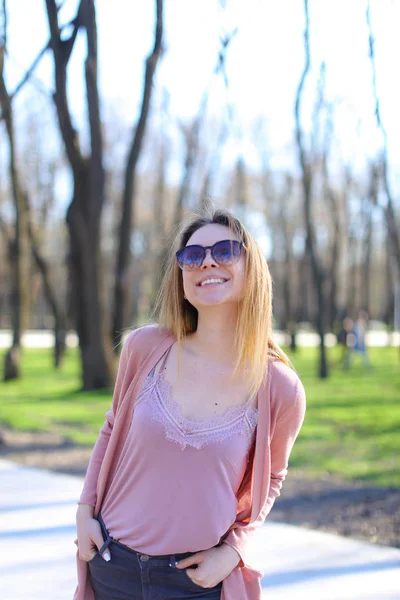 Mujer joven caminando en el parque y usando suéter largo . — Foto de Stock