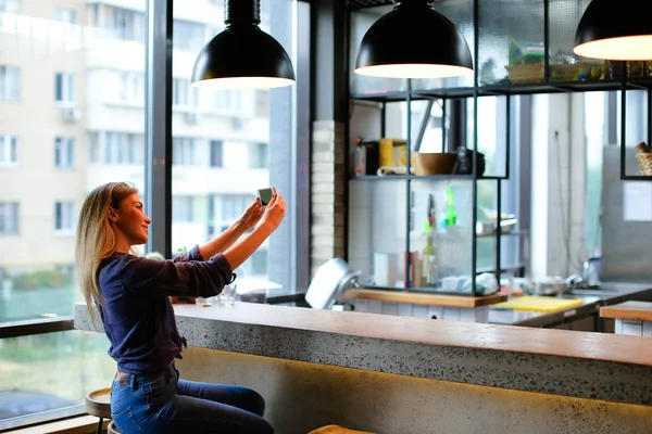 Junges Mädchen macht Selfie mit Smartphone in Café-Bar. — Stockfoto