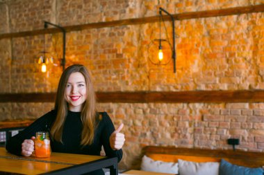 Limonata kafede fincan ile ahşap masa oturma ve rahatlatıcı memnun kız.