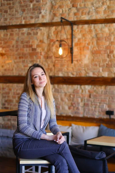 Chica satisfecha sentada cerca de la mesa en acogedora cafetería con un interior inusual . — Foto de Stock