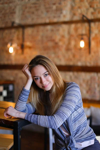 Nöjd tjej sitter nära tabell i mysiga café med ovanliga interiör. — Stockfoto