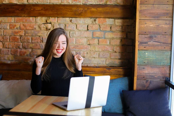 Chica afortunada con maquillaje regocijo con el ordenador portátil en la cafetería . — Foto de Stock