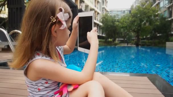 Meisje speelt met de Tablet PC in de buurt van zwembad. — Stockvideo