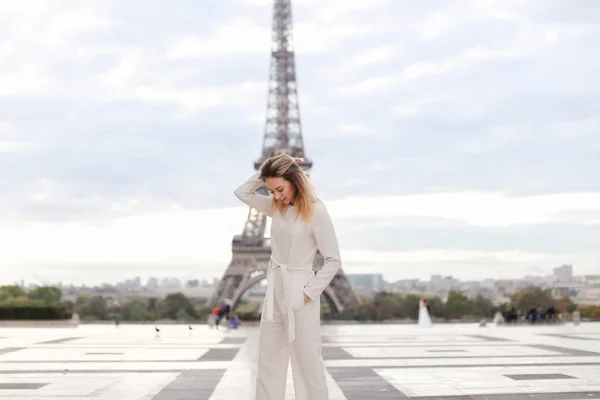 Chica con estilo de pie cerca de la Torre Eiffel en mono blanco . —  Fotos de Stock